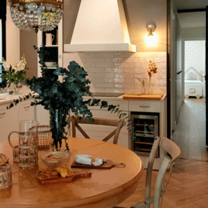 La cocina abierta combina alicatado, madera natural y mobiliario blanco. El separador de hierro negro estructura sin cerrar.