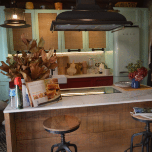 La cocina con isla central, papeles geométricos, muebles verdes y detalles rústicos.