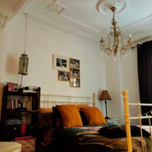 Dormitorio con aire vintage: forja blanca, lámparas de cristal y fotos familiares.