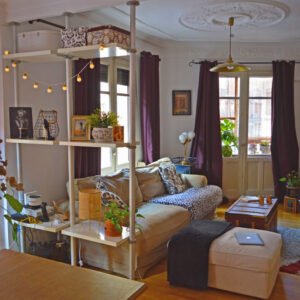 Espacio compartido con sofá esquinero, plantas y estantería decorativa.