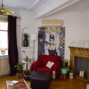 Rincón Hepburn: sillón burdeos, velas, y espíritu de cine clásico.